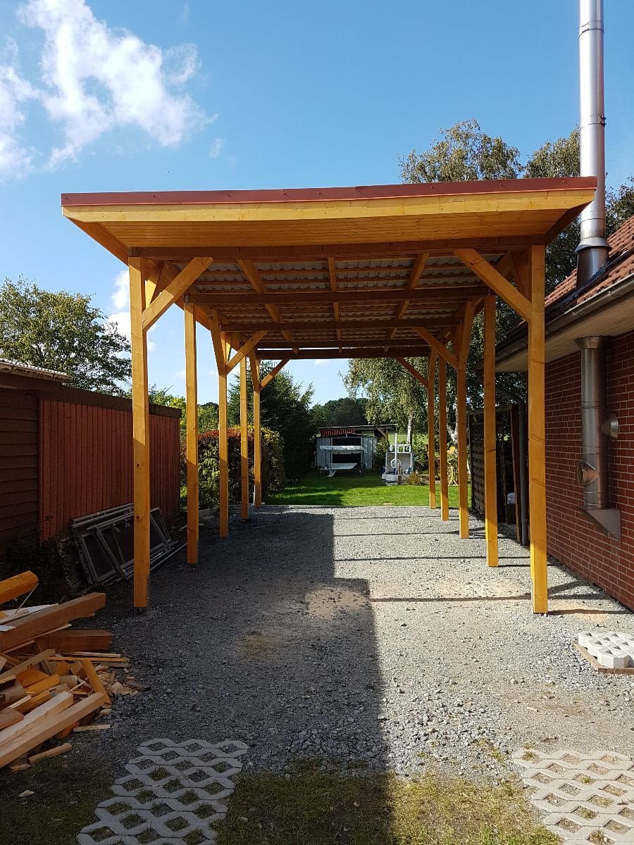 Neu gebauter Holz-Carport mit Kiesfläche und Rasengittersteinen