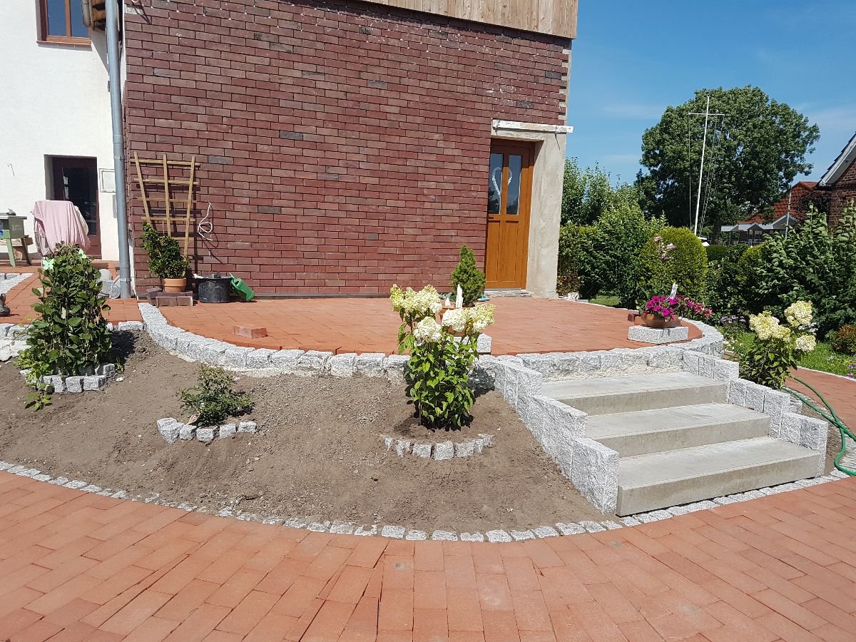 Granittreppe mit frisch angelegten Beeten und rotem Klinkerpflaster